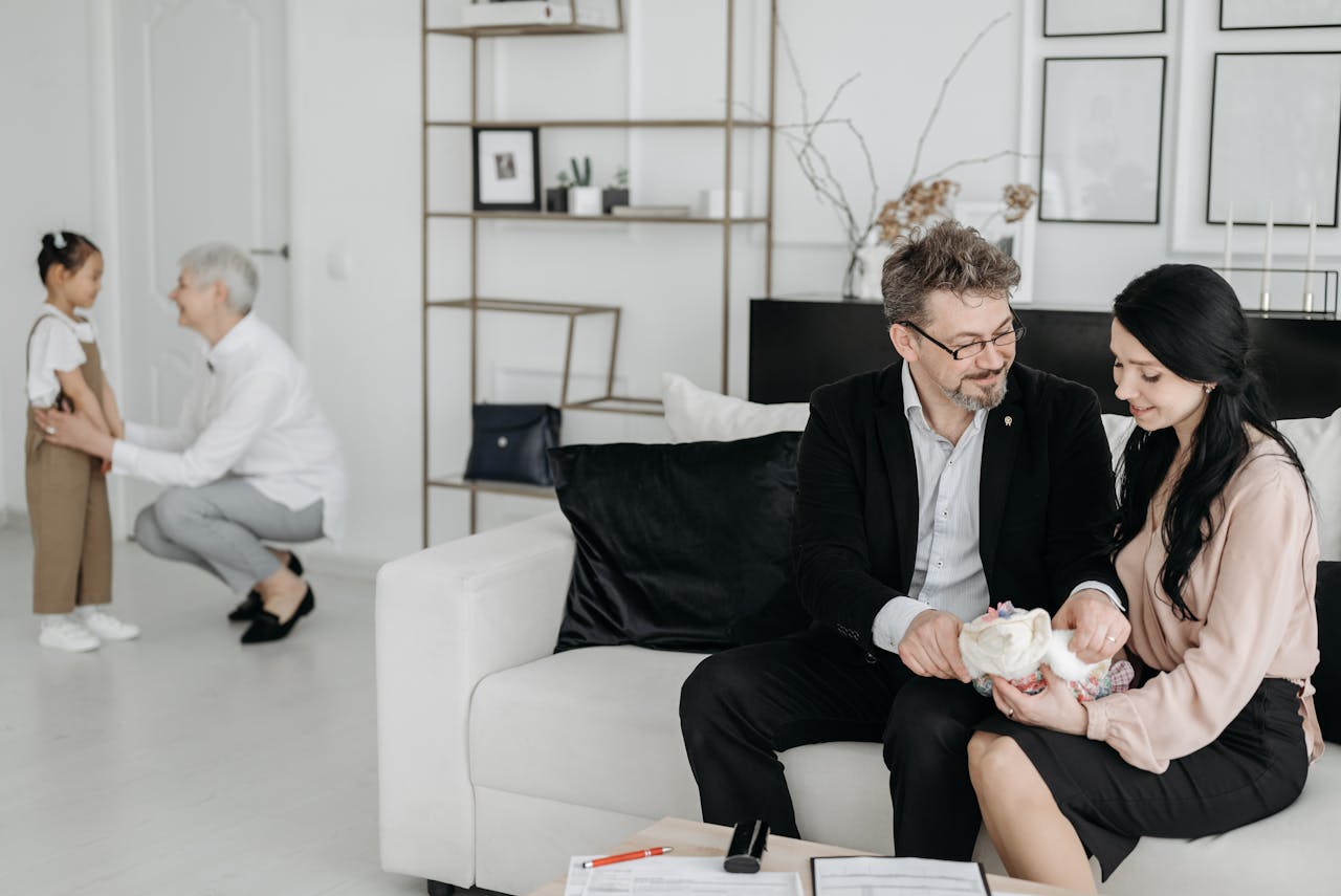 Couple with social worker and child, embracing new family moments in a cozy living room.