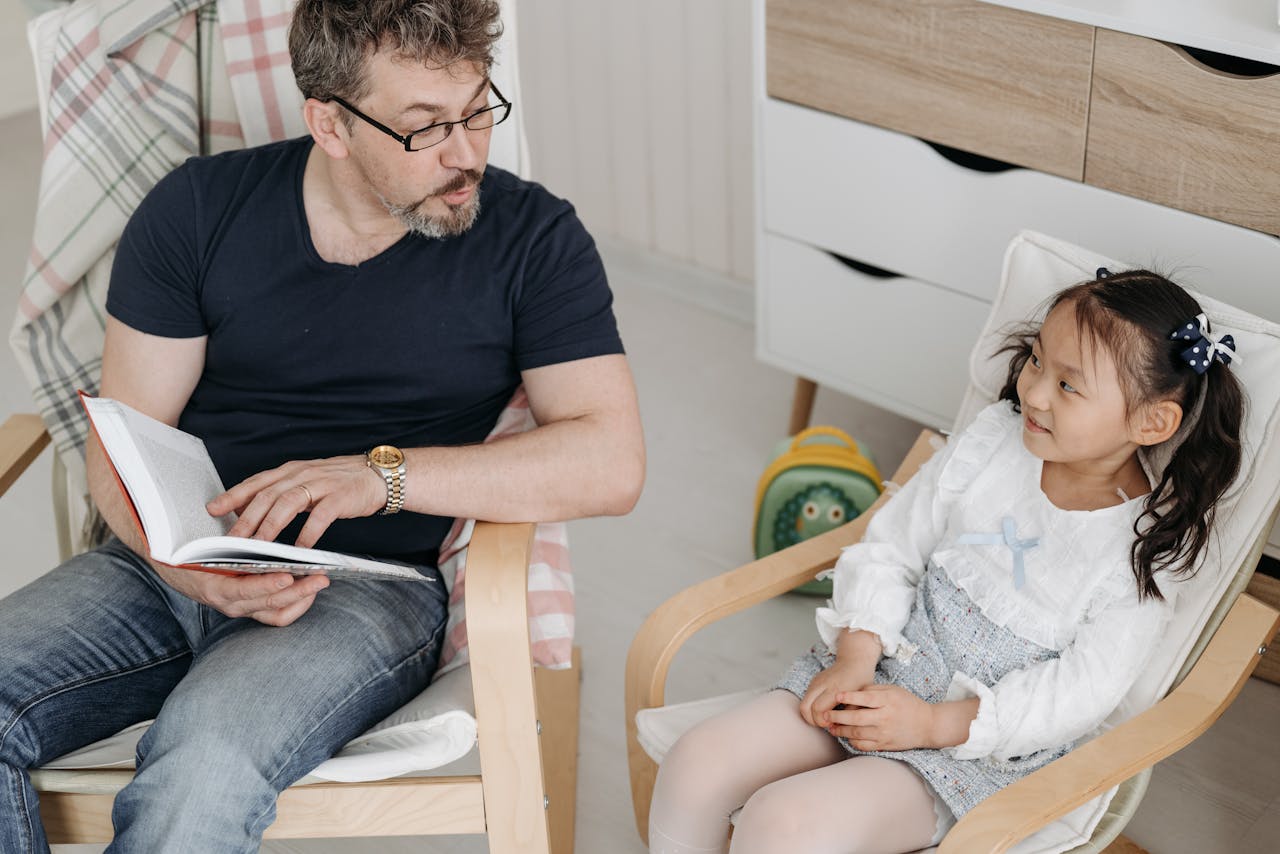 journey A father reading a book to his smiling daughter indoors, bonding activity.